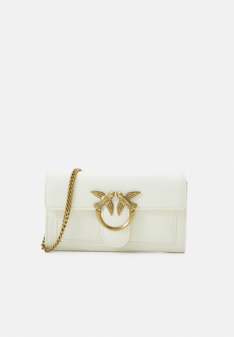 Balta ādas maks ar zelta toņa putna emblēmu un apļveida gredzenu. Tam ir ķēdes siksna un atloka aizdare. Gluda tekstūra.