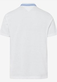 Polo blanc à manches courtes avec un accent bleu clair à l'intérieur du col, vu de dos.