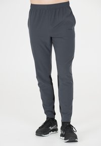 Grauathletische Hosen aus einem glatten, leichten Stoff. Verfügt über einen elastischen Bund, eng zulaufende Beine und schwarze Seiteneinsätze.