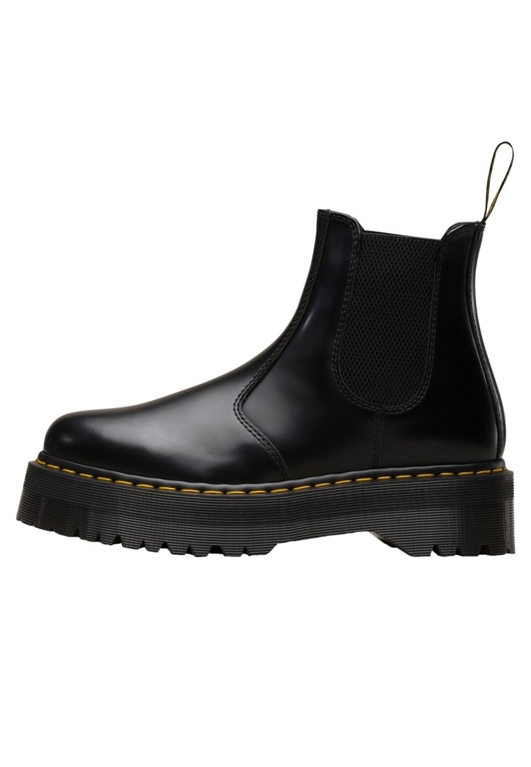 Botte Chelsea en cuir noir avec semelle épaisse rainurée, surpiqûres jaunes autour de la semelle, panneaux latéraux élastiques et languette de traction au talon.