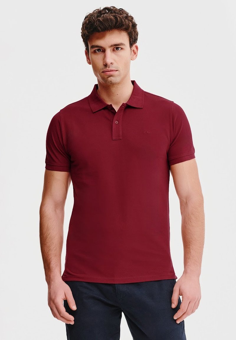 Bordowa koszula polo z klasycznym kołnierzykiem, krótkimi rękawami i subtelnym logo. Gładki materiał, dopasowany krój i brak widocznych wzorów.