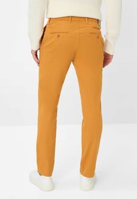 Heren slim-fit chino's van helder geel-oranje twillstof. Kenmerken zijn twee achterzakken met knopen en een gladde, rechte pijpdesign.