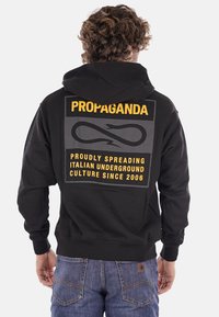 Felpa con cappuccio nera con grafiche stampate gialle e grigie sulla schiena. Presenta una vestibilità comoda ed è realizzata in tessuto morbido.