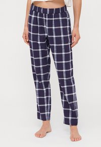 Marinblå rutig pyjamasbyxor med lös passform, elastisk midja och ljusblå accentfärger. Tillverkade av mjukt, andningsbart material.