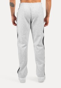 Grijze joggings met zwarte zijstrepen, elastische tailleband en rechte pijpen, gemaakt van zachte, gestructureerde stof.