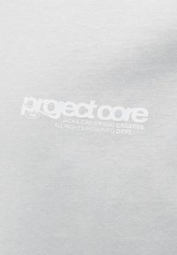 Lys grå bomulds t-shirt med hvid tekst, der står "projectcare" og "JACK & JONES © 1990 CREATIVE" i et moderne skrifttype.