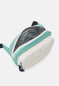 Texturerad väsk med två fack i mintgrön och krämfärgad. Har en smidig dragkedja, marinblå rem och ett rymligt inre med tygfoder.