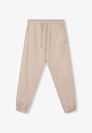 Pantalons de survêtement beiges avec une taille élastique, un cordon de serrage réglable et des poignets de jambe fuselés. Présente un petit logo en relief sur le côté.
