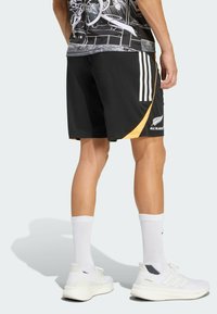 Černé sportovní šortky s žlutým akcentem a třemi bílými pruhy. Vyrobené z lehkého materiálu, s elastickým pasem.