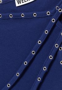 Μπλε ναυτικό ριμπ τοπ με ασημένιες λεπτομέρειες από επιθετικούς κρίκους κατά μήκος του ντεκολτέ και της πλευράς, με απαλό υλικό και δομημένο σχεδιασμό.