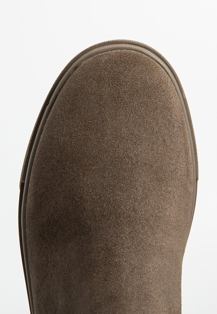 Braune Wildleder-Stiefelette mit runder Zehenpartie, glatten Kanten und einer geriffelten Gummisohle. Die Textur wirkt weich und samtig.