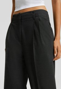 Svart skräddarsydda byxor med veck, tillverkade av texturerad tyg. Har en rak skärning och midjehöjd. Passar bra för formella tillfällen.