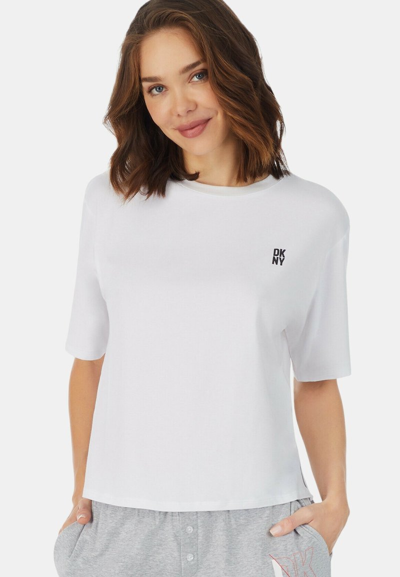 Witte katoenen t-shirt met een ronde hals en korte mouwen, voorzien van een klein zwart DKNY-logo op de linkerborst. Casual pasvorm en een gladde textuur.