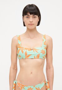 Haut de bikini en teal clair avec des motifs floraux orange, décolleté carré, bretelles larges, et un subtil détail de logo métallique au centre.