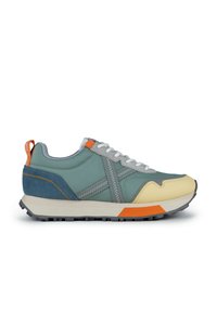 Zapatilla multicolor con una mezcla de materiales en azul claro, gris y amarillo, con una suela de goma, acentos texturizados y costuras en contraste.