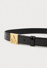 Crni ko�žni pojas s sjajnom površinom, s zlatnom pravokutnom kopčom ugraviranom s "Armani Exchange" i geometrijskim izrezima.