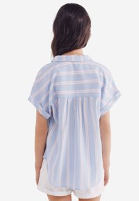 Camicia azzurra chiaro con righe verticali rosa e bianche, maniche corte, colletto e design sul retro arricciato. Tessuto di cotone liscio.