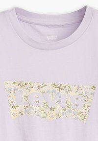 Camiseta lavanda de Levi's con logo de patrón floral en tonos suaves de azul, verde, amarillo y marrón en el pecho, debajo del cuello redondo.