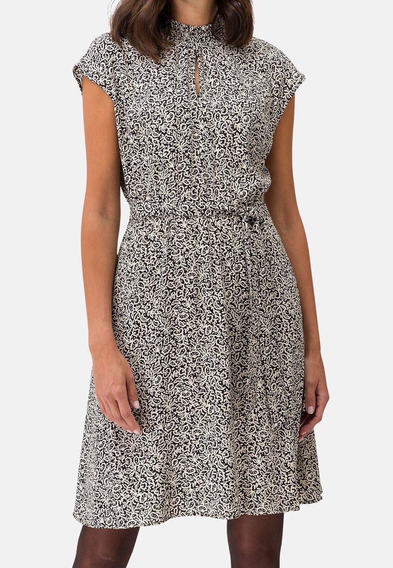 Zwart-wit gestreepte jurk met een hoge kraag, korte mouwen en een sleutelgatopening bij de hals, strakker aan de taille.