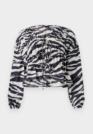 Izrezana bluzica u bijeloj i tamnoplavoj zebri, s nabranošću, dugim rukavima i naglašavanjem s vezicama sprijeda i u struku.