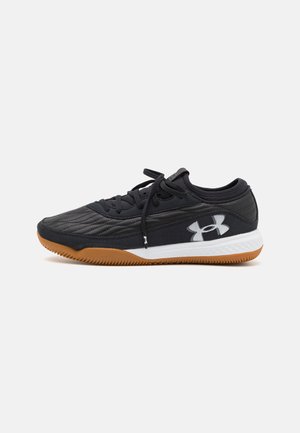 Czarny but sportowy z gumową podeszwą, białą podeszwą środkową, sznurowanym przodem i dużym białym logo Under Armour po boku.