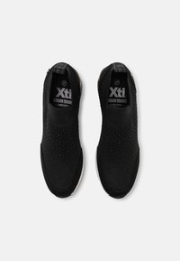 Czarne sneakersy wsuwane z teksturowaną siateczką, kontrastującą białą podeszwą i subtelnymi perforacjami zapewniającymi oddychalność. Z logo Xti.