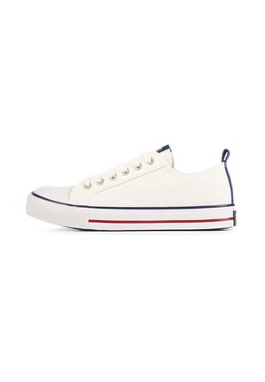 Zapatilla de lona blanca con punta redondeada, cinco agujeros para cordones, acentos en color azul marino y rayas rojas sobre una suela de goma blanca. Incluye un lazo trasero para facilitar el calzado.