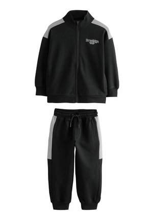 Black tracksuit set featuring a zip-up jacket with gray shoulder accents and matching elastic waist pants with pockets. Made of soft fabric.