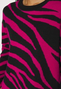 Maglione nero con un motivo a strisce di zebra rosa. Il tessuto sembra morbido con una consistenza liscia e un classico design a girocollo.