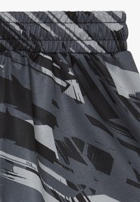 Lähikuva joustavasta vyötärönauhastaan mustassa ja harmaassa abstraktissa kuvioläikässä, jossa on näkyvissä koottu ja ommeltu yksityiskohta.