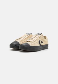 Baskets en daim beige avec capuchon et semelle en caoutchouc noir. Présente un logo étoile noir et le branding "ALL STAR" sur la languette. Design à lacets.