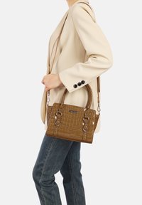 Borsa marrone con motivo coccodrillo, dotata di doppi manici, tracolla staccabile e dettagli metallici; presentata su uno sfondo neutro.