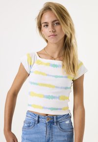 Witte cropped top met korte mouwen, versierd met horizontale pastelstrepen in geel, blauw en groen. Draag het met lichtblauwe denim shorts.