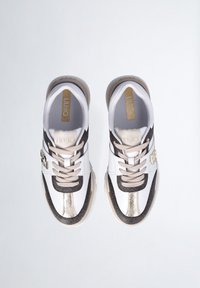 Zapatillas deportivas en blanco y negro, con acentos metálicos dorados, patrones texturizados y un diseño con cordones y suelas acolchadas.