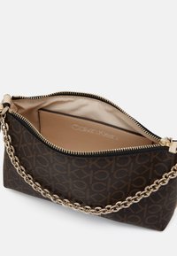 Ruskeakuvioinen keinonahkainen käsilaukku, jossa on kullanvärinen ketjuhihna, vetoketjusulku ja beige vuori. Sisältää nahkaisen korttikotelon.