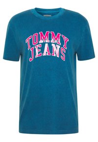 Camiseta de algodón turquesa con cuello redondo y mangas cortas. Presenta letras en negrita en blanco y rosa que dicen "TOMMY JEANS" en el pecho.