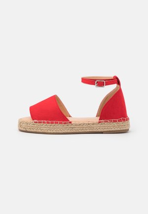 Rød lærred espadrillesandal med ankelrem, åbent tådesign, jutesål og syet detalje langs kanten.