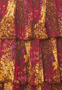 Tissu marron avec des motifs vibrants de rose, jaune et orange. Présente des plis et des volants, créant texture et intérêt visuel.