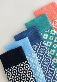 Calcetines de lana coloridos con patrones: azul marino con flores blancas, azul claro geométrico, verde azulado con acentos blancos, azul oscuro texturizado, y coral acanalado.