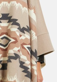 Wollmischung-Cape mit geometrischen Mustern in Beige, Braun und Marineblau. Entworfen mit einem weiten Schnitt und großen vorderen Knopfverschlüssen.