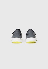 Zapatillas deportivas grises con una textura suave, suelas blancas y detalles en amarillo neón. Tienen un diseño de corte bajo y recortes laterales para ventilación.