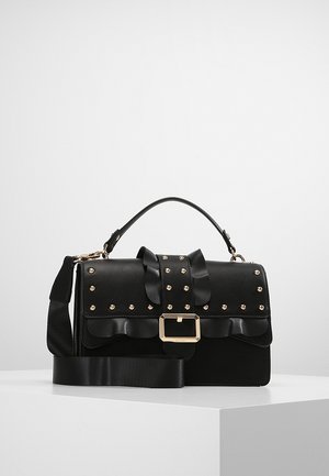 Czarna skórzana torebka z złotymi ćwiekami, marszczoną klapą, prostokątną złotą klamrą, górnym uchwytem oraz odpinanym szerokim paskiem na ramię na białej powierzchni.