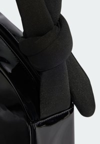 Black patent leather handbag with a knotted black fabric strap, glossy finish, and visible zipper along the side.