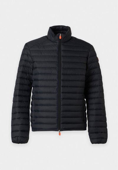 Veste légère matelassée noire avec col montant, fermeture éclair intégrale devant et poignets élastiques, présentée sur fond blanc.