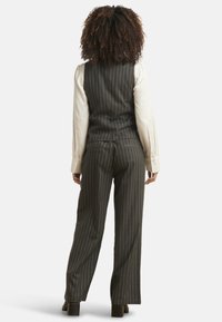 Tailored pinstriped vest and pants in dark gray with contrasting white long-sleeve shirt. Straight-leg design with functional back pockets.