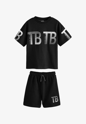 Conjunto de sudadera de algodón negro y pantalones cortos que presenta "TB" en letras a rayas blancas en la parte delantera y lateral. Incluye una cinturilla elástica.