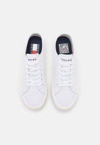 Sneakers bianchi in tela con design a lacci, suole in gomma e soletta blu navy con logo del marchio e codice QR.