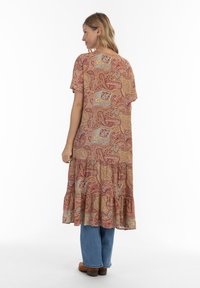 Lang, løstsiddende kjole i et paisley-mønster med nuancer af rød, guld og blå. Den har korte ærmer og en flæset nederste kant med flere lag.