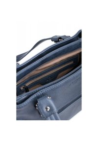 Blauwe leren tas interieur met lichte stoffen voering, voorzien van een ritsvak en kaartslots. Gestikte accenten en metalen hardware zichtbaar.