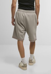 Grå bomuldsshorts med elastisk talje, der har kontrasterende rød syning langs benåbningerne. Bæres med hvide crew-sokker og sneakers.